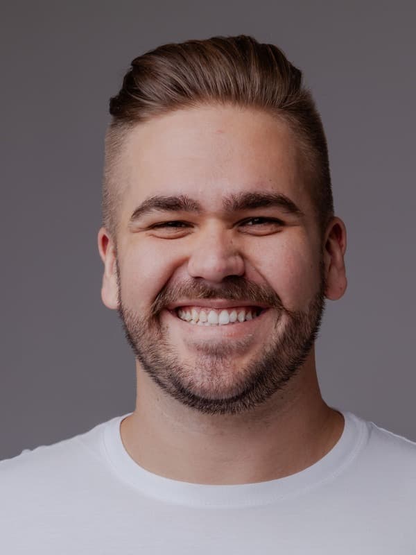 Matheus Fischer, smiling, white t-shirt, gray studio background